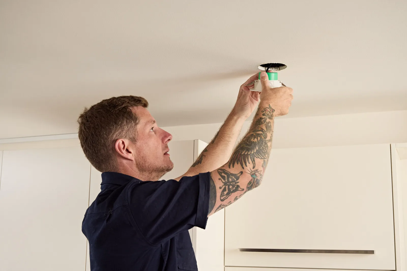 Ceiling smoke alarm being fitted by an electrician